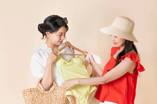 ファッションを着たアジア系の2人の女の子が黄色の水着をチェックし — ストック写真