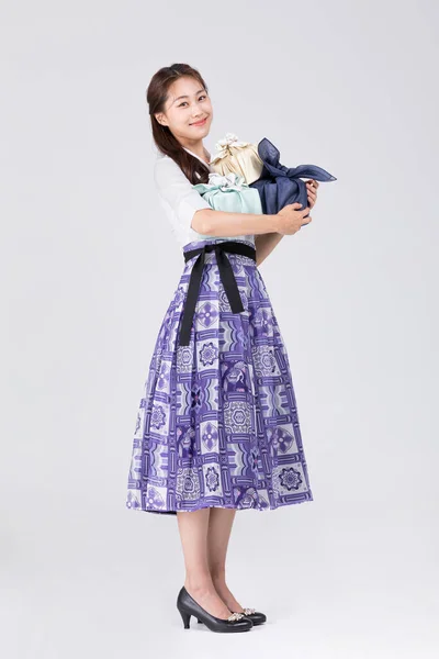 beautiful Korean woman in 20s wearing modern Hanbok, holding gift box