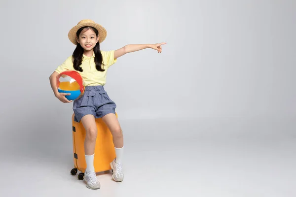 韩国女孩穿着运动服在白色的背景音乐演播室 拿着一个海滩球坐在职业上 — 图库照片