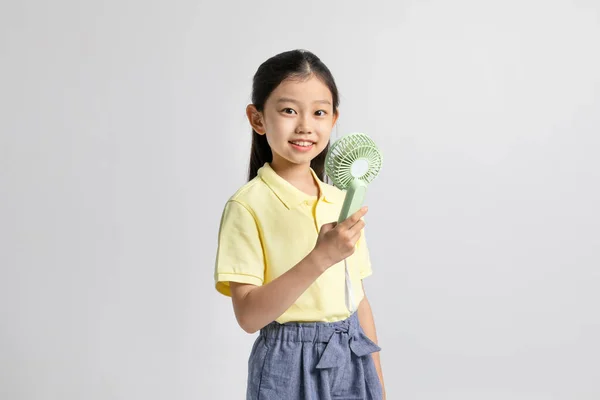 韩国女孩穿着白色背景工作室的运动服 手持便携式风扇 — 图库照片
