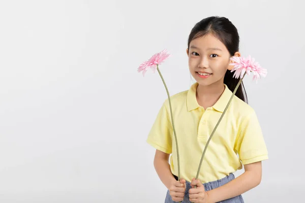韩国小女孩穿着运动服在白色的背景音乐演播室 手持鲜花 — 图库照片