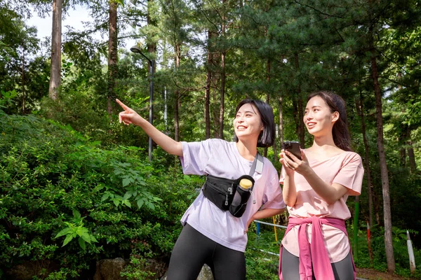 20代の韓国人女性の友人2人がハイキングや山へのプラグイン パス検索スマートフォンを使用して ストックフォト