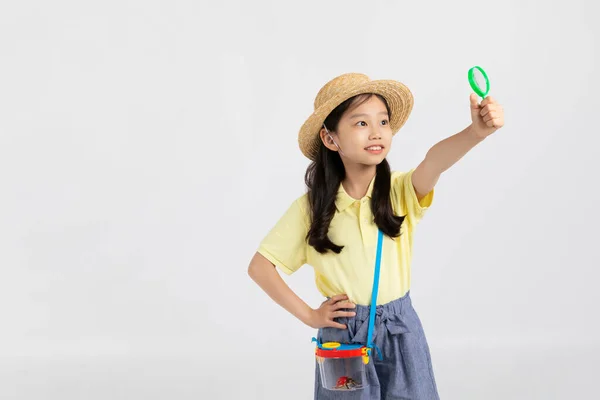 韩国小女孩穿着白色背景工作室的运动服 用放大镜观察昆虫 — 图库照片