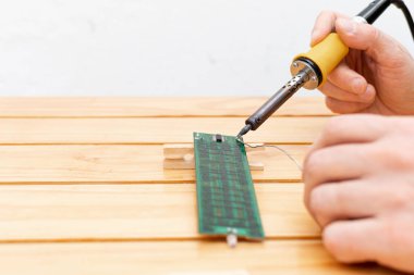 Eller elektronik devreyi elektrik lehimleme demiri ve teneke ile lehimliyor.