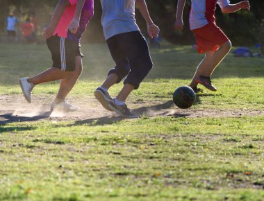 Gençler parkta tutkuyla futbol oynuyorlar.