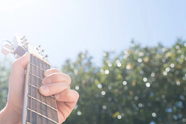 Selective Focus Hand Holding Acoustic Guitar Outdoors Sky Greenery Background — Stock Photo, Image