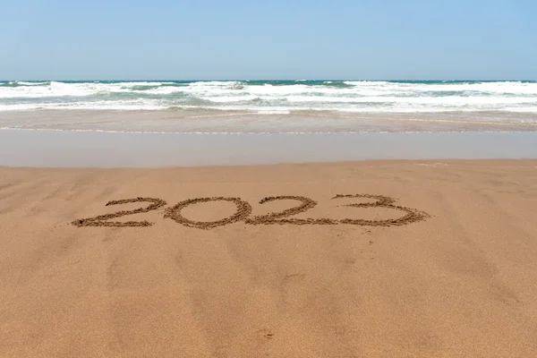 Yıl 2023 Sahilde kumsalda, arkada deniz yazılıydı.