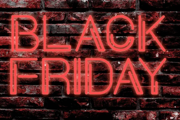 Neon letters advertising black friday on a brick wall.