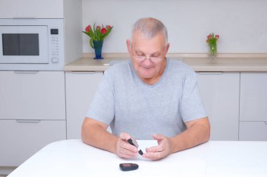 Yaşlı adam kan şekerini ölçüyor.