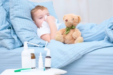 Oğlan yatakta yatıyor, hasta, boğazı ağrıyor, ateşi var ve sulanıyor.