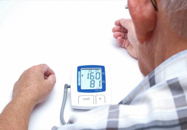 Yaşlı bir adam kan basıncını ve nabzını ölçer..