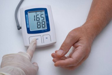 Yaşlı bir adam kan basıncını ve nabzını ölçer..