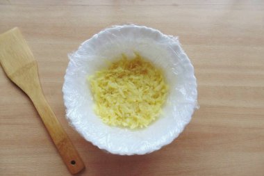 Kristal sertleşirken, salatayı hazırla. Patatesleri üniformalarında kaynatın, soğusun, soyun ve rendeleyin. Salata kasesine yapışkan film yerleştirin ki kenarları sarkık olsun. Patatesleri bir kaseye koy..