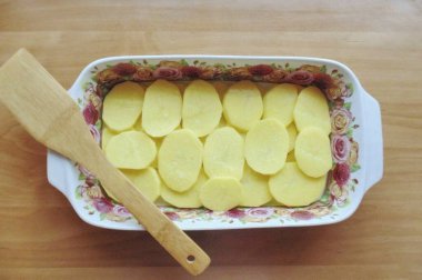 Pişirme kabını sebze yağıyla yağla, dilimlenmiş patatesleri ayır.