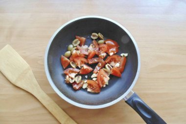 Tavuğu bir tabağa aktarın. Tavaya doğranmış domates, zeytin ve sarımsak koy..