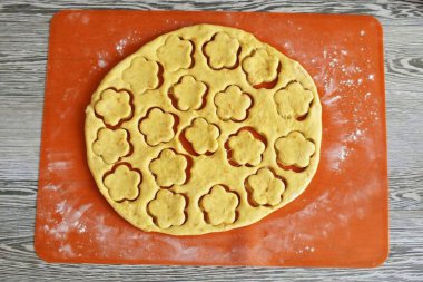 Hamuru iki parçaya böl. Her parçayı 0.5 cm kalınlığında bir katmana yuvarla. Kurabiyeleri kurabiye keskisiyle kes..