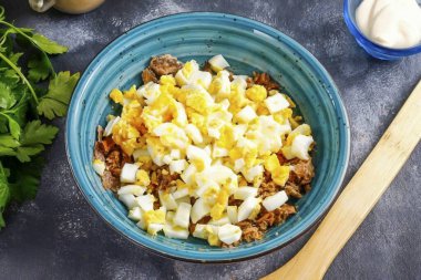 Haşlanmış tavuk yumurtası soy ve suda durula. Küçük küplere ayırın ve dilimleri balık kütlelerine bir kaseye boşaltın..