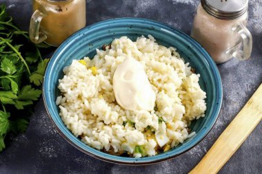 Haşlanmış pirinç ve yağlı mayonez koyun. Tüm malzemeleri nazikçe karıştır..