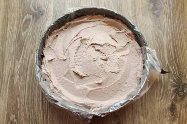 Küfün kenarlarını plastik folyoyla kaplayın. Kremi alt katmana aktar ve düzleştir..