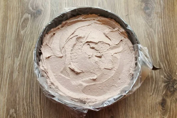 Küfün kenarlarını plastik folyoyla kaplayın. Kremi alt katmana aktar ve düzleştir..