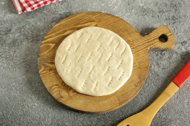 Hamur parçalarına un serp ve küçük bir parmak kadar kalın pastaları yuvarla. 5-7 dakika saklan ve dinlen. Pastaların çok fazla şişmesini önlemek için çatal batırabilirsin..