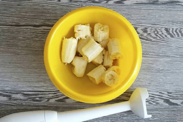 剥皮香蕉 碎成碎片转移到一个碗 用手搅拌机在泥上打孔 — 图库照片