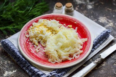 Orta rende haşlanmış patatesleri soy ve rendele. Tavuk yumurtasını soy ve rendele..