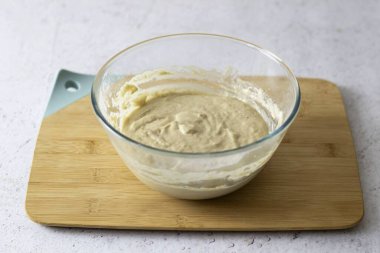 Unu bir kaseye boşalt ve pürüzsüz, yumru yumru olmayan bir hamura yoğur. Son olarak, sebze yağını dök ve tekrar karıştır. Hamurun yoğunluğu orta kalınlıkta olmalı ve çok fazla yayılmamalı..