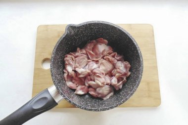 Tavuk midesini işleyin. Yağ, toplardamar, film, varsa. İyice yıka ve ağır bir tencereye koy..