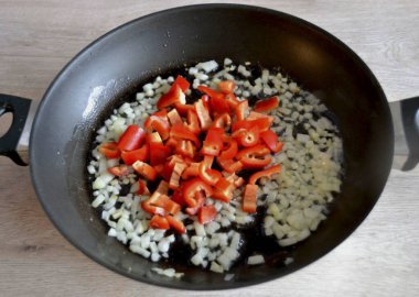 Soğan hafifçe kahverengileştiğinde, doğranmış (çok ince olmayan) dolmalık biber ekle.