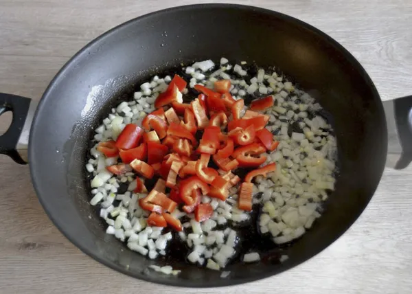 Soğan hafifçe kahverengileştiğinde, doğranmış (çok ince olmayan) dolmalık biber ekle.