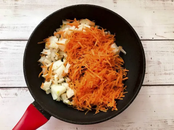 Peel the onion. Wash the carrots well, peel and grate on a medium grater. Place vegetables in a well-heated skillet with vegetable oil and fry for 10 minutes.