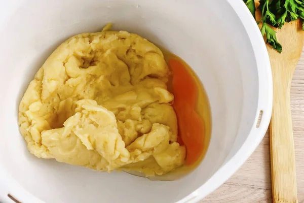 Place the dough into the bowl of a food processor or mixer, beat in a chicken egg and stir into the dough at high speed.
