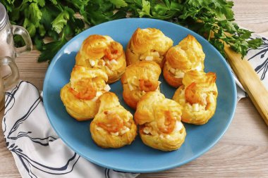 Profiterolleri soğut, kapaklarını kes ve hazırlanmış kütle ile doldur. Tabağa ya da tabağa koy.