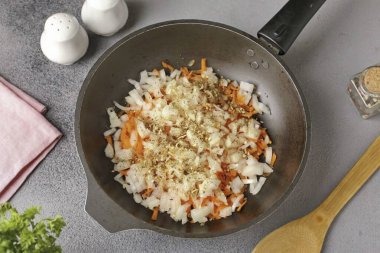 Soğanları doğra, havuçları rendele, sebzeleri önceden ısıtılmış bir tavaya koy ve baharat ekleyene kadar yağda kızart..