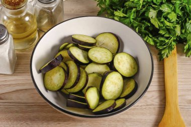 Patlıcanları suyla yıka, sebzelerin kuyruklarını kes ve 1 cm 'den kalın olmasın. Dilimleri derin bir kaba koy..