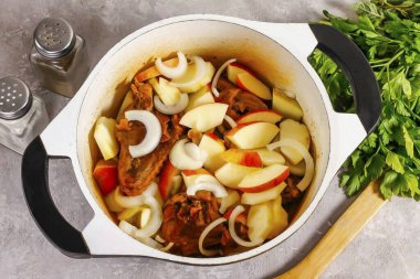 Ördek eti hassaslaştığında, elmaları çeyrekliklere ayır, tohum bloklarını kes ve suda durula. Büyük dilimlere ayırın ve soğanı yarım halkalara bölün ve kabın içine ekleyin..