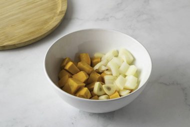 Kabağı soy, küp küp doğra. Soğan ve sarımsağı da soy, küçük dilimlere böl..