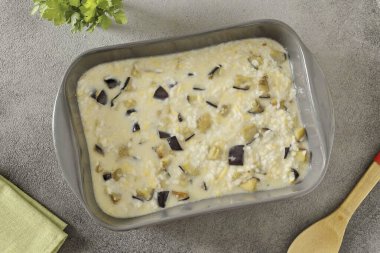 Patlıcan, pirinç ve yumurta sütü karışımını birleştir. Yağ geçirmez bir tabağa koy ve fırına koy. Alt ve yan tarafına ekmek kırıntıları serpiştirilebilir..