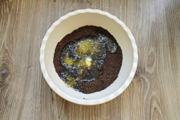 Измельчите печенье в мелкие крошки любым удобным способом. Отложите 100 граммов крошек, налейте в оставшееся охлажденное масло и перемешать.