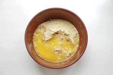 Tereyağını erit ve kurabiye kırıntılarına dök. Her şeyi pürüzsüz, yapışkan olana kadar karıştır.