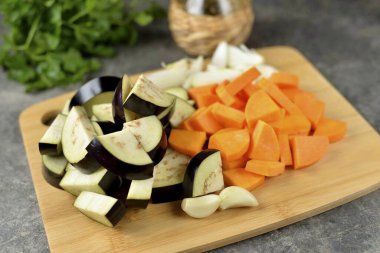 Kabağı soy, patlıcanı küçük dilimlere ayır, soğan ve sarımsağı da doğra..