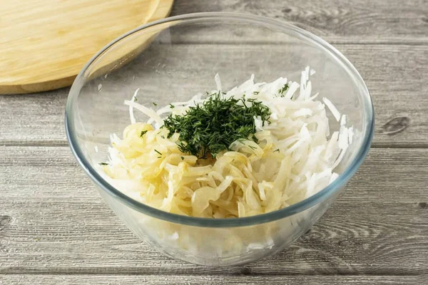 Drain the water, fold the radish onto a sieve and squeeze out of the water. Transfer to a deep bowl. Add fried onions and finely chopped dill. Season the salad with vegetable oil, salt and pepper. Mix thoroughly.