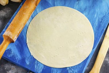 Şu anda, hamuru dondurucudan çıkar ve eşit parçalara böl. Her parçayı çok ince bir katmana yuvarla. Daireleri bir tabakla kes ve çatalla batır..