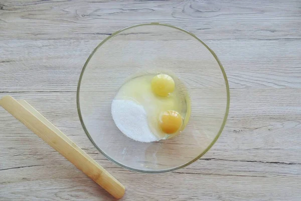 Pour sugar into a bowl and break the eggs.