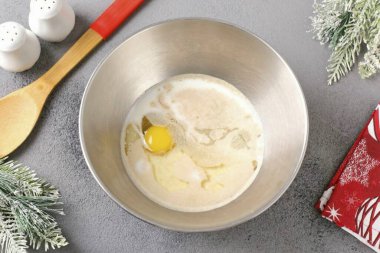 Sıcak sütü, bir yumurtayı, tuzu, şekeri, sebze yağını ve mayayı derin bir kasede birleştirin..