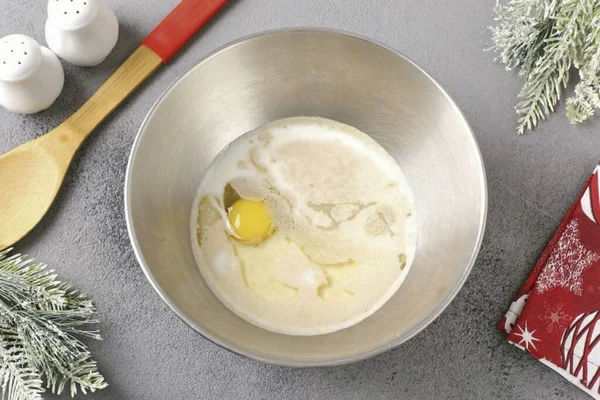 Sıcak sütü, bir yumurtayı, tuzu, şekeri, sebze yağını ve mayayı derin bir kasede birleştirin..