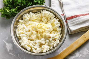 Yağlı içerikli süzme peyniri derin bir kâseye ya da salata kasesine koy. Oraya da mayonez ekle, tuz. Sarımsaklı karanfilleri soy, durula, kabın içine bastır..