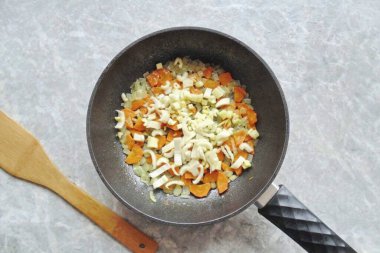 Kereviz sapını yıka, küçük daireler çiz ve soğan ve havuç ekle, karıştır ve 5-7 dakika daha kaynat..