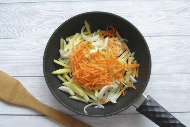 Peel the carrots, rinse and grate. Add to potatoes. Peel the onion, wash and cut into half rings. Add to skillet. Pour in sunflower oil and place over medium heat. Fry, stirring occasionally, until half cooked.